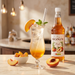 Monin Peach Syrup 1L lifestyle — peach Italian soda mocktail | Addtocart Dubai UAE